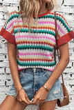 Person wearing a colorful striped sweater and denim shorts with a white brick wall background