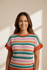 Woman wearing a colorful striped sweater against a neutral background
