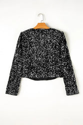 Black sequin top on a hanger against a white background