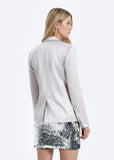 Woman wearing a light gray blazer and sequin skirt on a white background