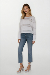 Woman wearing a light gray striped sweater and blue jeans on a white background