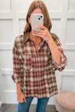 A woman takes a mirror selfie wearing a brown and rust-red plaid button-up shirt with a solid brown collar, paired with blue jeans.