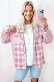 Woman wearing a pink plaid shirt taking a selfie on a light pink background