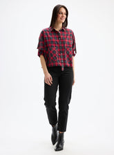 Woman wearing a red and black plaid shirt with black pants on a white background