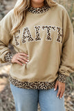 Woman wearing a beige sweatshirt with leopard trim and “FAITH” lettering, paired with light blue jeans.