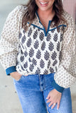 Woman wearing a floral blouse with blue accents and jeans, standing against a neutral background.