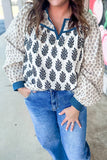Person wearing a patterned blouse and blue jeans with a blurred background