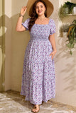 Woman in a floral dress standing outdoors with plants in the background