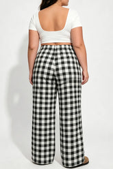 Person wearing a white top and black and white checkered pants on a white background