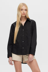 Woman wearing a black shirt and beige shorts on a white background