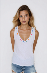 Woman wearing a white tank top with colorful accents against a plain background