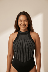 Woman wearing a black halter-neck swimsuit with bead detailing on a beige background