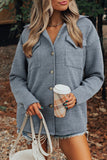 Woman wearing a gray textured jacket holding a coffee cup outdoors.