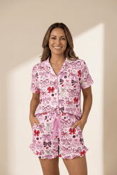 Woman wearing a pink pajama set with bow pattern on a beige background
