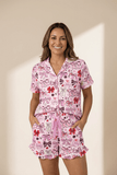 Woman wearing a pink pajama set with bow pattern on a beige background