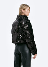 Person wearing a black sequin puffer jacket on a white background