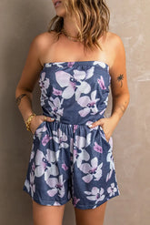 Woman wearing a strapless floral romper against a neutral background