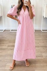 Woman wearing a pink and white striped dress in a store setting.