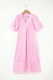 A pink and white vertically striped short-sleeve dress hanging on a wooden hanger against a plain white wall.