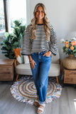 Woman wearing a striped sweater and jeans standing in a living room.