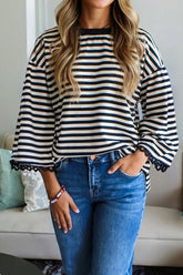Person wearing a black and white striped sweater and blue jeans indoors.