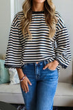 Person wearing a black and white striped sweater and blue jeans indoors.