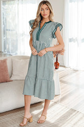 Woman wearing a green and white striped dress in a bright living room.