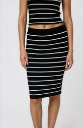 Person wearing a black and white striped top and skirt on a white background