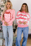 Woman in pink “Merry & Bright” sweatshirt with red gift graphic and light blue jeans.
