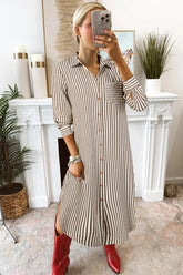 Woman taking a mirror selfie wearing a striped dress and red boots in a home setting.