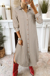 Person wearing a long striped shirt dress with red shoes in a home setting.