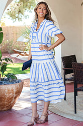 Woman in a blue and white striped dress standing outdoors.