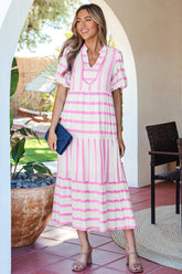 Woman in a pink and white striped dress standing outdoors.