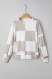Checkered sweater on a hanger against a gray background