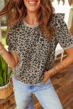 Woman wearing a leopard print shirt and light blue jeans indoors.