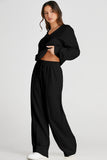 Woman wearing a black outfit with wide-leg pants on a white background