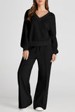 Woman in black V-neck loungewear set with wide-leg drawstring pants.