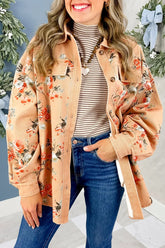 Woman in beige floral button-up shirt jacket, striped turtleneck and blue jeans with holiday greenery.