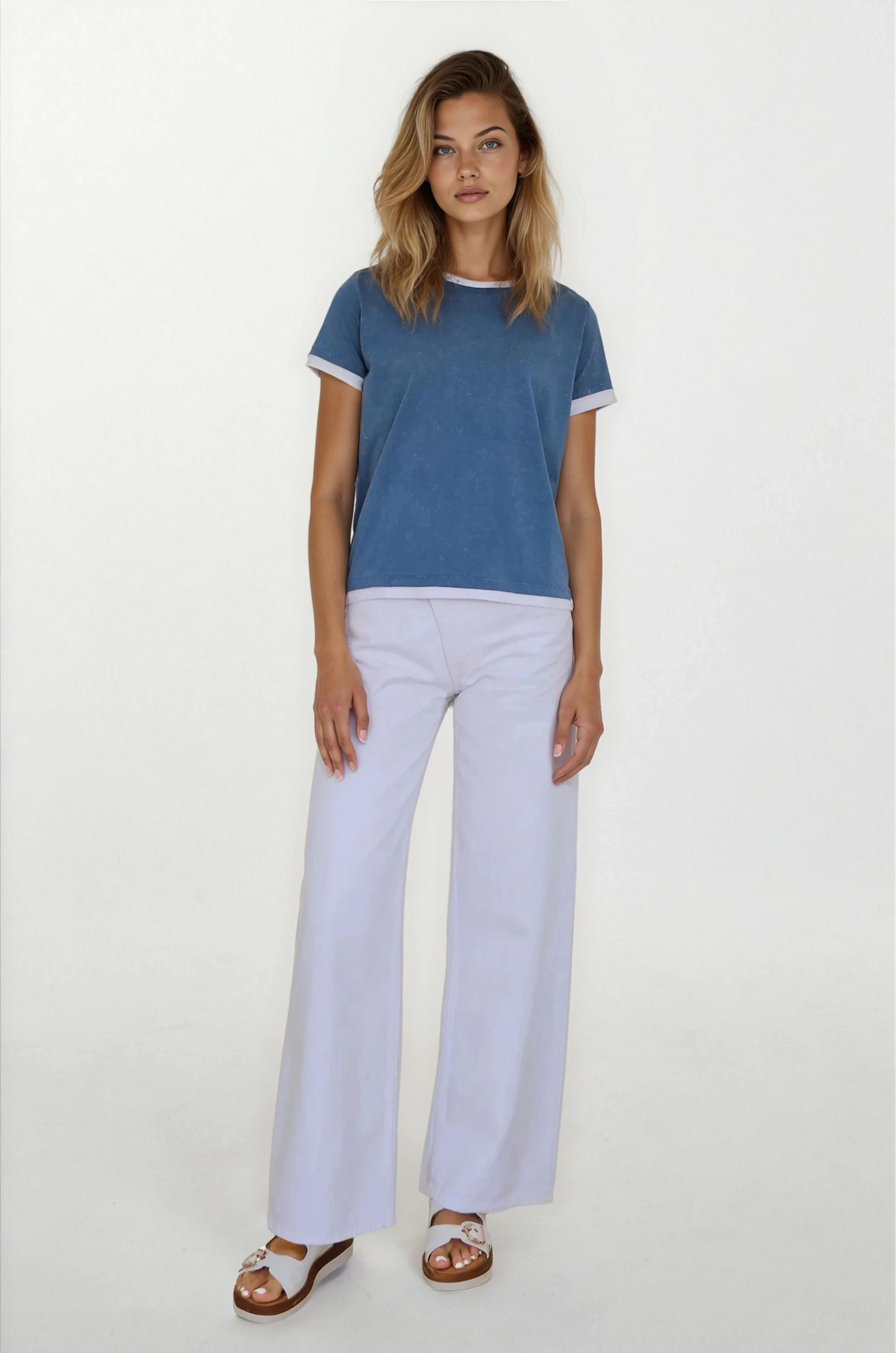 Woman wearing a blue t-shirt and white pants on a white background