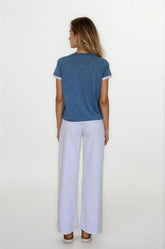 Woman wearing a blue top and white pants on a white background