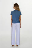 Woman wearing a blue top and white pants on a white background