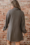 Woman wearing a gray coat against a brick wall