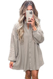 Woman taking a selfie wearing a long-sleeve button-up shirt dress on a white background