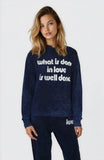 Woman wearing a navy sweatshirt with white text on a white background