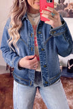 Woman taking a mirror selfie in a blue denim jacket, graphic T-shirt, and light-wash jeans