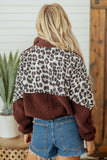 Back view of woman in brown leopard-print fleece jacket with denim shorts.