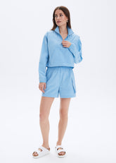 Woman wearing a light blue outfit with shorts on a white background