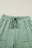 Green lounge pants with drawstring waist on a light beige background