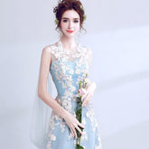 Woman in a light blue floral dress holding flowers against a plain background