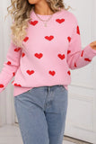 Person wearing a pink sweater with red heart patterns and blue jeans.